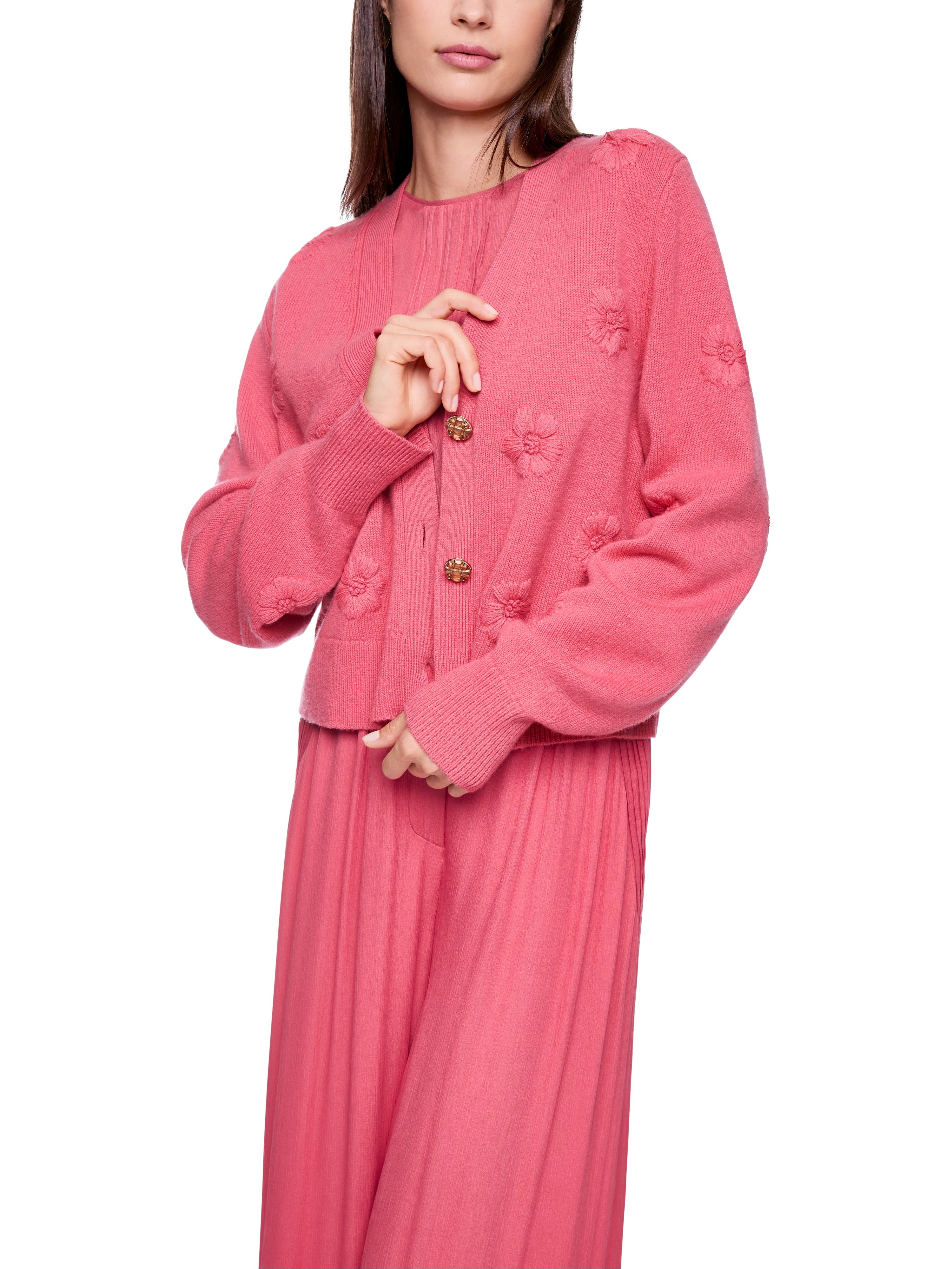 קרדיגן אלגנטי בצבע ורוד עמוק, בגזרה רפויה עם מחשוף V ודוגמת פרחים רקומיםבעיטור כפתורי זהב עם קריסטליםהרכב בד: 90% צמר בתולי, 10% קשמירהדוגמנית בגובה 1.79 מ' ולובשת מידה 3 של מארק קיין