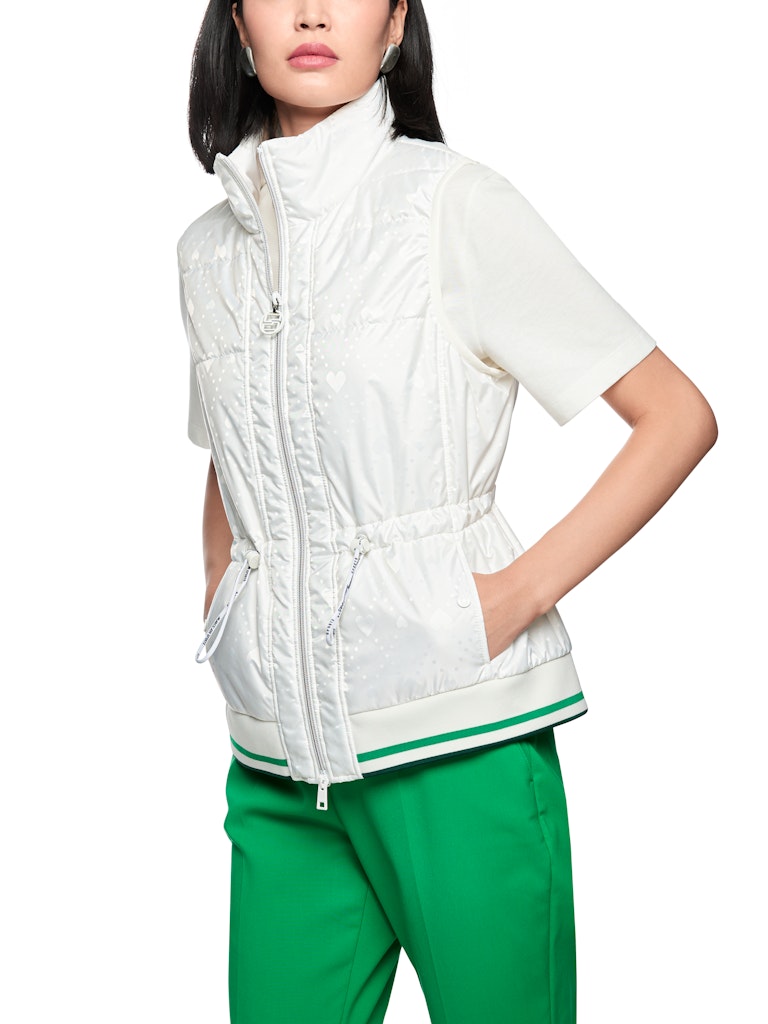 וסט מרופד בעיצוב ספורטיבי, עם הדפס בדוגמת לבבות. גזרה ישרה, עם שרוכי גומי מתכווננים במותניים להתאמה אישית, צווארון עומד, כיסים צדדיים הניתנים לסגירה, ורוכסן דו כיווני, בגימור מנג'ט ארוג בדוגמת פסים צבעוניים.הרכב: 65% פוליאמיד, 35% פוליאסטרהדוגמנית בגובה 1.79 ולובשת מידה 3 של מארק קיין