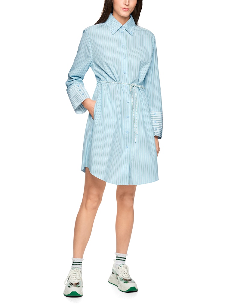 שמלת מיני בעיצוב קז'ואל-מודרני, בסגנון חולצה מכופתרת בדוגמת פסי סיכה בגוון ירוק, עשויה כותנה טהורה ונעימה במיוחד. גזרה רחבה ונינוחה, עם שרוך קשירה במותן, שרוולים ארוכים בסיומת חפתים מכופתרים רחבים המאפשרים התאמת אורך אישית, כיסי צד, וצווארון קלאסי.הרכב: 100% כותנההדוגמנית בגובה 1.79 ולובשת מידה 3 של מארק קיין