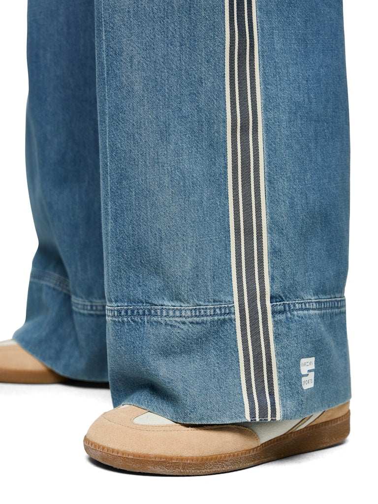 מכנסי ג'ינס בגזרת Wide Cut, רחבה ומשוחררת, עם מותן גבוהה, עשויים בד רך וזורם.המכנסיים בעיצוב ספורטיבי, עם רצועת מותן אלסטית ורחבה עם שרוך קשירה, תוספת דיטיילס של פס בד לאורך הרגל ורקמה על הכיס האחורי, 2 כיסים צידיים ו-2 כיסים אחוריים.הרכב: 64% כותנה, 36% ליוסלהדוגמנית בגובה 1.79 ולובשת מידה 3 של מארק קיין