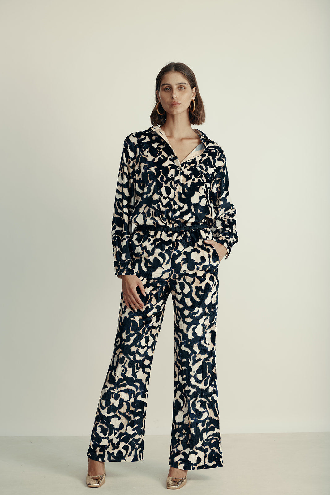 מכנסי קטיפה מתרחבים עם רצועת מותן בהדפס ורדיםהרכב: 75% ויסקוזה, 25% פוליאסטר; בד משני: 60% אצטט, 40% ויסקוזההדוגמנית בגובה 1.80 ולובשת מידה 40 איטלקית (מידה I של פורטה פורטה)