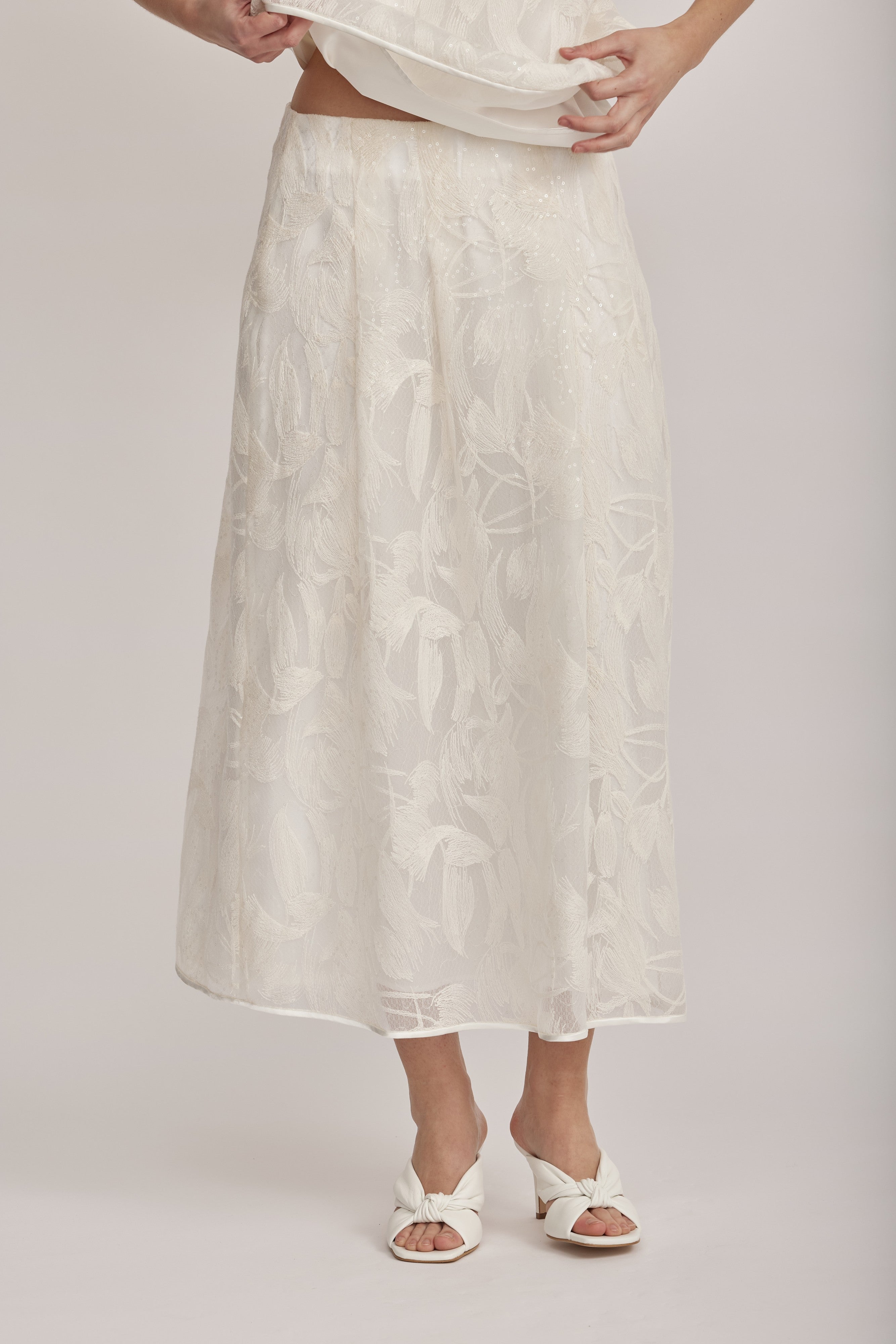 חצאית מקולקציית ה-Runway של המותג האיטלקי PESERICO, בעיצוב דו-שכבתי המשלב בד טול שקוף מעוטר ברקמה עדינה עם פאייטים בדוגמת עלים, ובד אורגנזה דק וקליל בגוון תואם, היוצר משחקי טקסטורה ושקיפויות, ומראה ייחודי.החצאית באורך מידי, בגזרה מתרחבת ונינוחה, עם קפלים מודגשים, בטנה פנימית, וסגירה באמצעות רוכסן צידי נסתר.הרכב: טול- 50% פוליאמיד, 50% כותנה, אורגנזה- 100% פוליאסטר, בטנה- 97% פוליאסטר, 3% אלסטןהדוגמנית בגובה 1.75 ולובשת מידה 42 של PESERICO