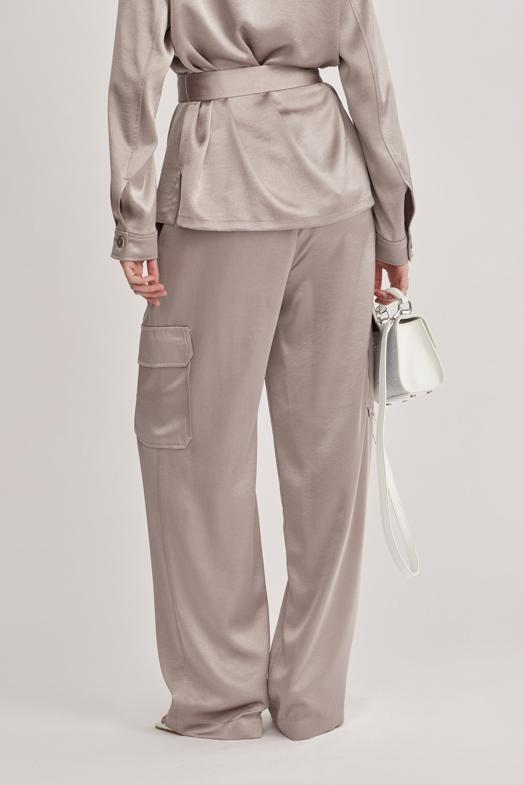 מכנסיים מבית המותג RIANI, בעיצוב מודרני ואלגנטי בסגנון מכנסי קרגו, מבד סאטן רך וגולש בעל ברק מטאלי עדין. גזרה ישרה, עם כיסים צידיים וכיסי קרגו גדולים בצידי הרגל, לולאות לחגורה, וסגירה נסתרת.הרכב: 100% פוליאסטרהדוגמנית בגובה 1.75 ולובשת מידה 36 אירופאית