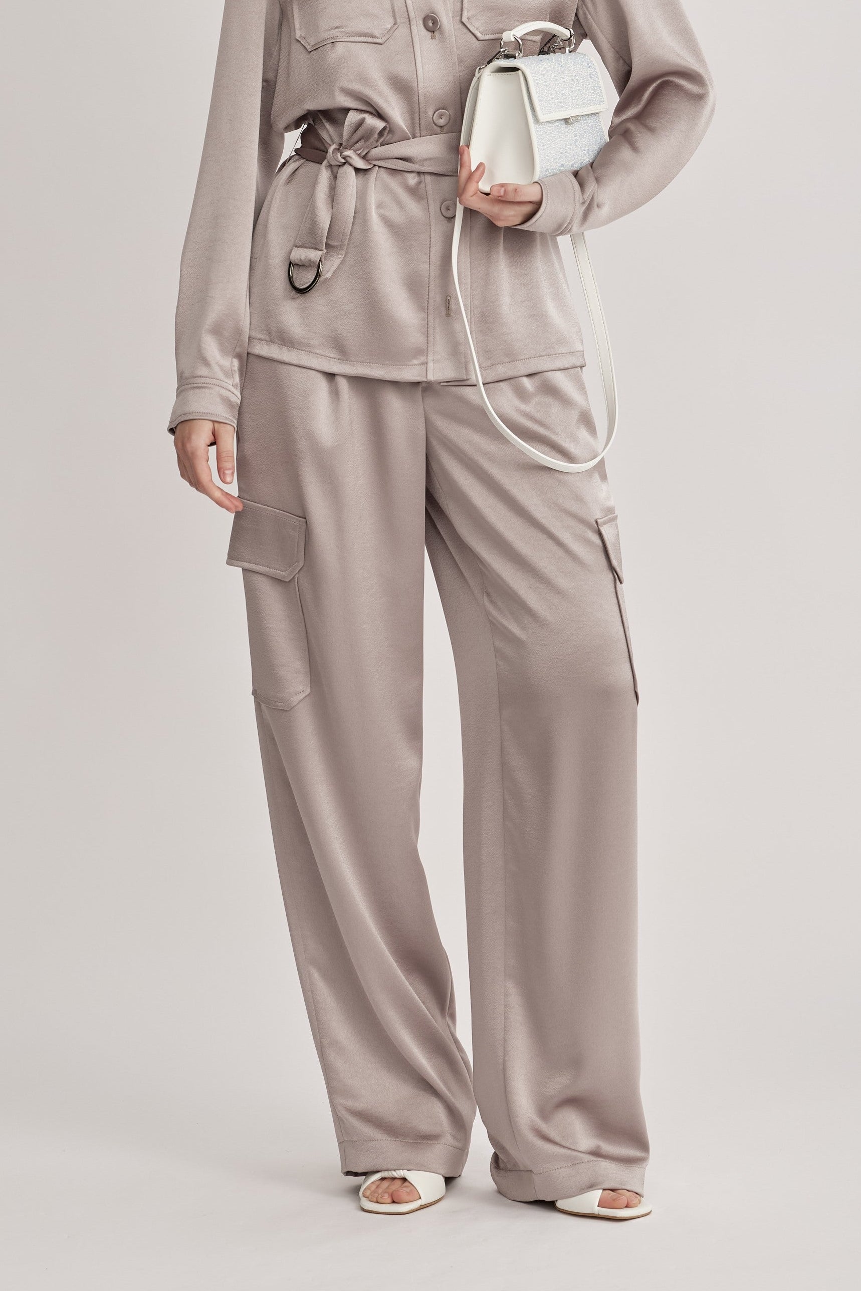 מכנסיים מבית המותג RIANI, בעיצוב מודרני ואלגנטי בסגנון מכנסי קרגו, מבד סאטן רך וגולש בעל ברק מטאלי עדין. גזרה ישרה, עם כיסים צידיים וכיסי קרגו גדולים בצידי הרגל, לולאות לחגורה, וסגירה נסתרת.הרכב: 100% פוליאסטרהדוגמנית בגובה 1.75 ולובשת מידה 36 אירופאית