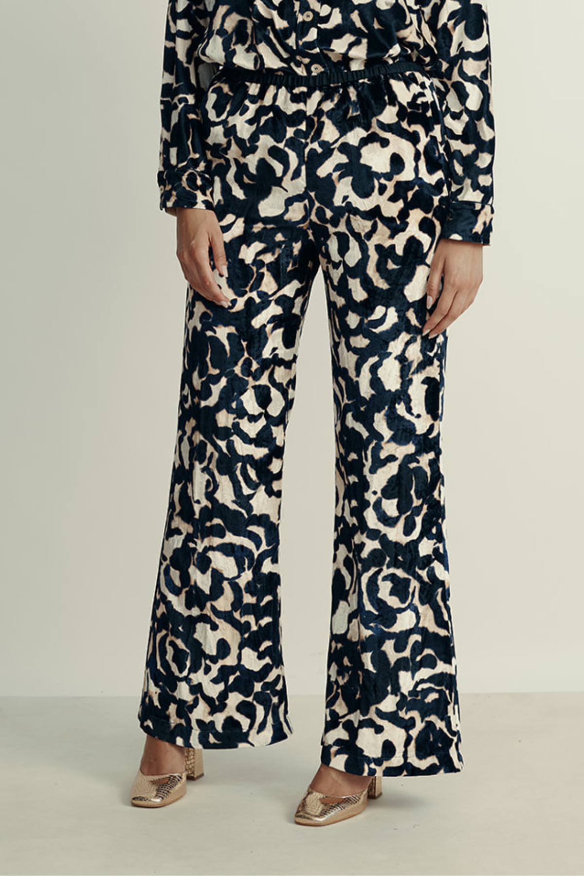 מכנסי קטיפה מתרחבים עם רצועת מותן בהדפס ורדיםהרכב: 75% ויסקוזה, 25% פוליאסטר; בד משני: 60% אצטט, 40% ויסקוזההדוגמנית בגובה 1.80 ולובשת מידה 40 איטלקית (מידה I של פורטה פורטה)