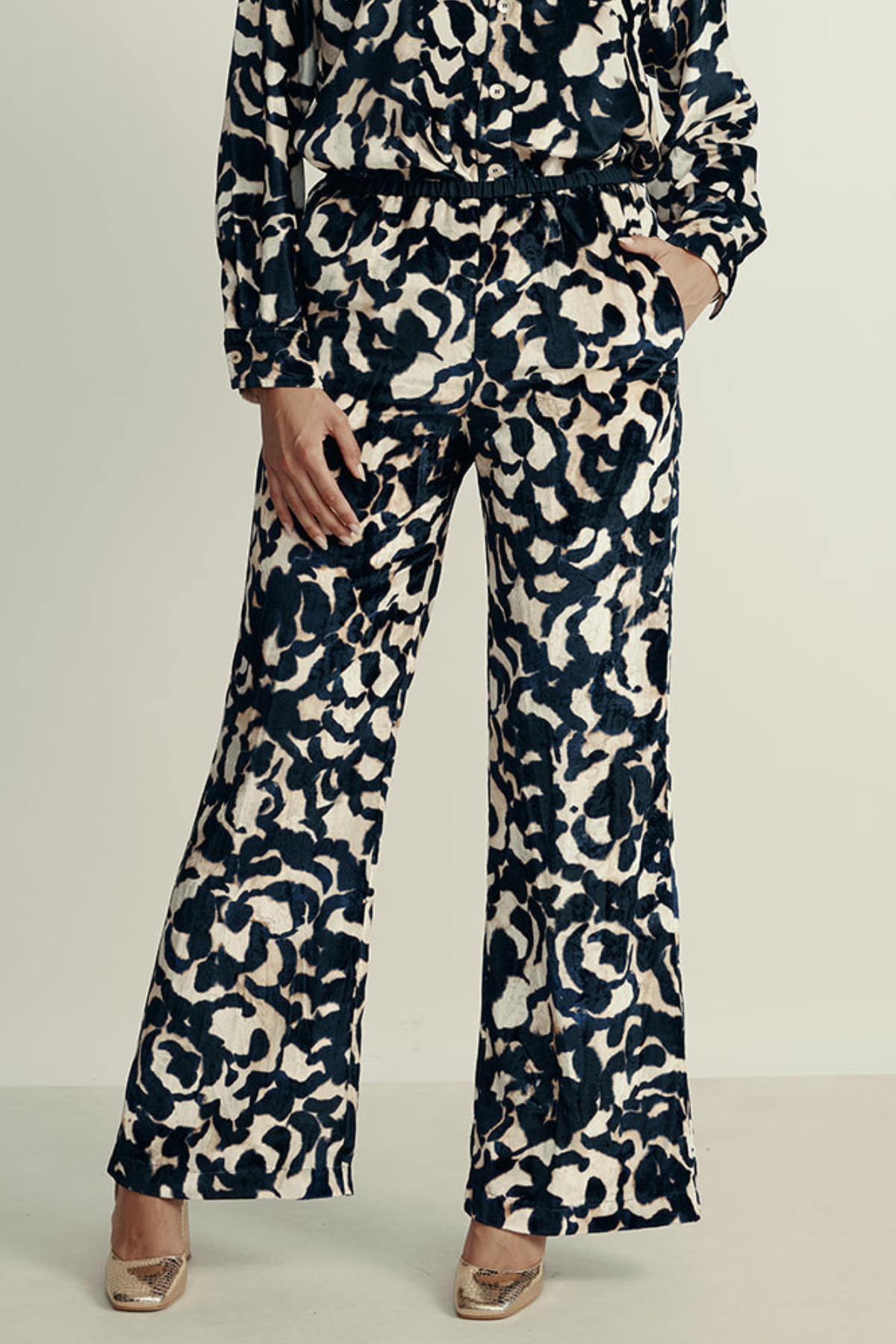 מכנסי קטיפה מתרחבים עם רצועת מותן בהדפס ורדיםהרכב: 75% ויסקוזה, 25% פוליאסטר; בד משני: 60% אצטט, 40% ויסקוזההדוגמנית בגובה 1.80 ולובשת מידה 40 איטלקית (מידה I של פורטה פורטה)