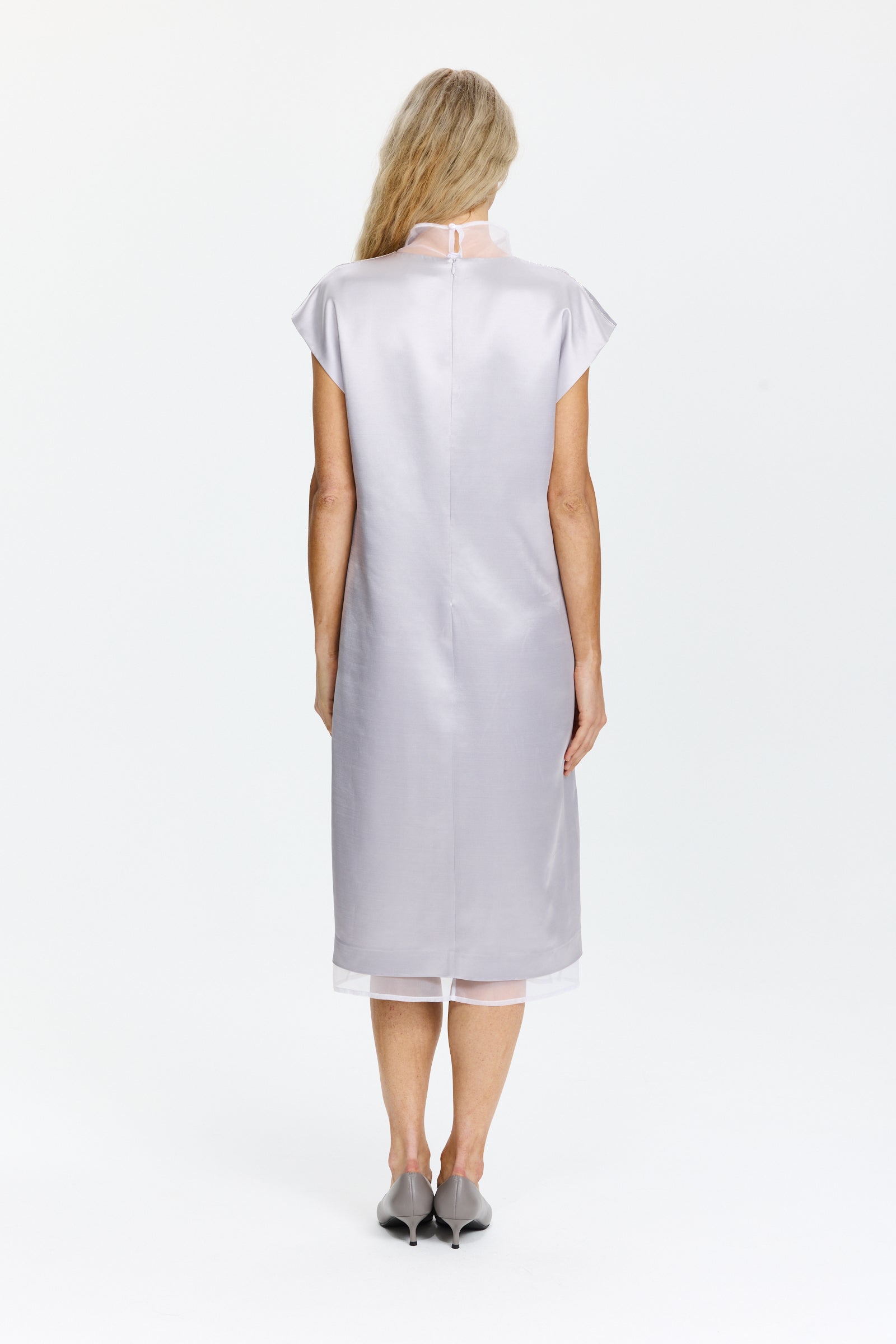 שמלה ללא שרוולים באורך מידי, מחשוף V עם צווארון עומד, סגירת רוכסן וכפתור, וכיסים אלכסוניים. כוללת שכבת בטנה פנימית הניתנת לשליפההרכב בד: 77% ויסקוזה, 23% צמר בתוליהדוגמנית בגובה 1.75 ולובשת מידה 42 של Peserico