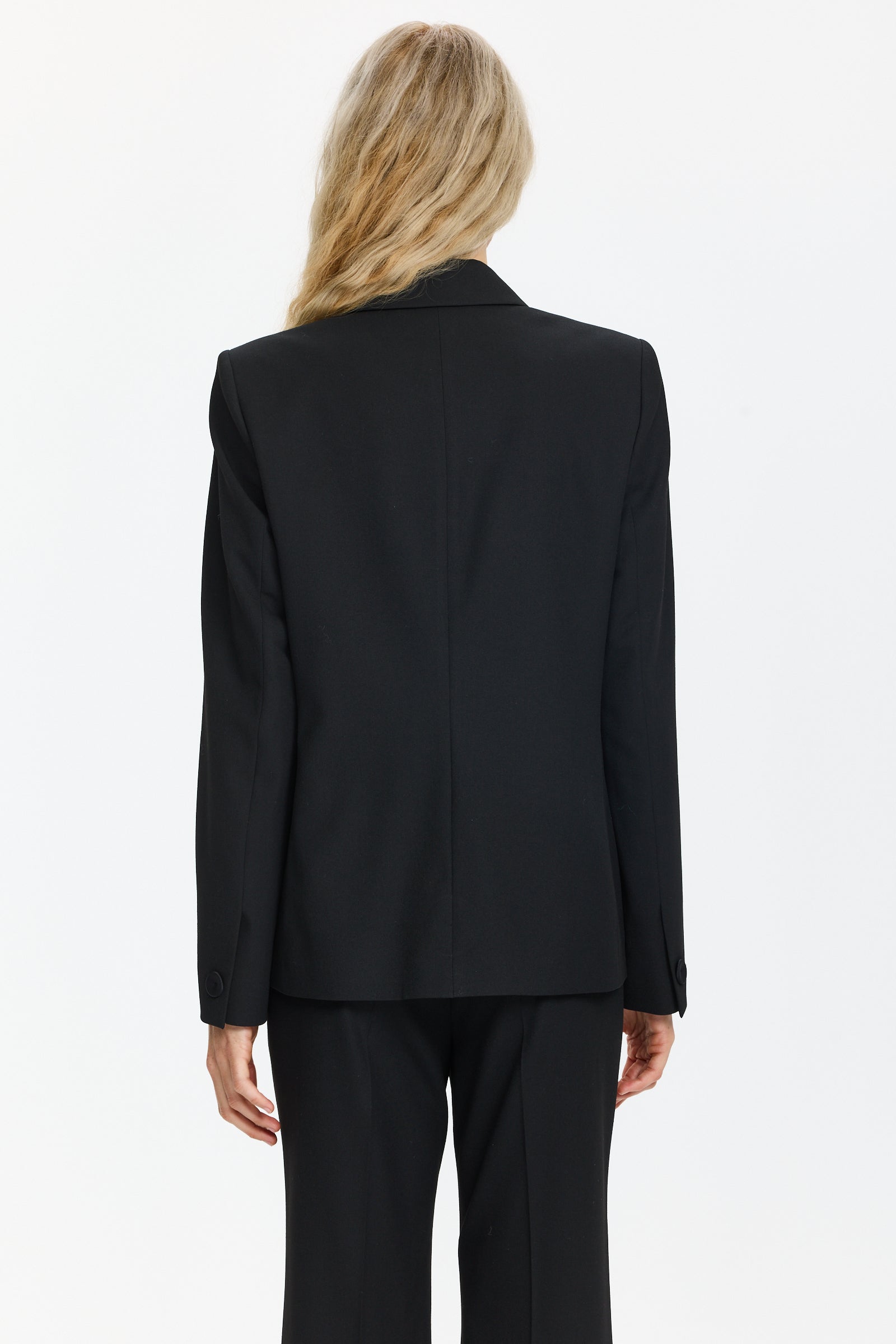 בלייזר טוקסידו בצבע שחור עם סגירה כפולה, שני כיסים וכריות כתףהרכב הבד: 67% פוליאסטר, 29% ויסקוזה, 4% אלסטןהדוגמנית בגובה 1.75 ולובשת מידה 36 של Luisa Cerano