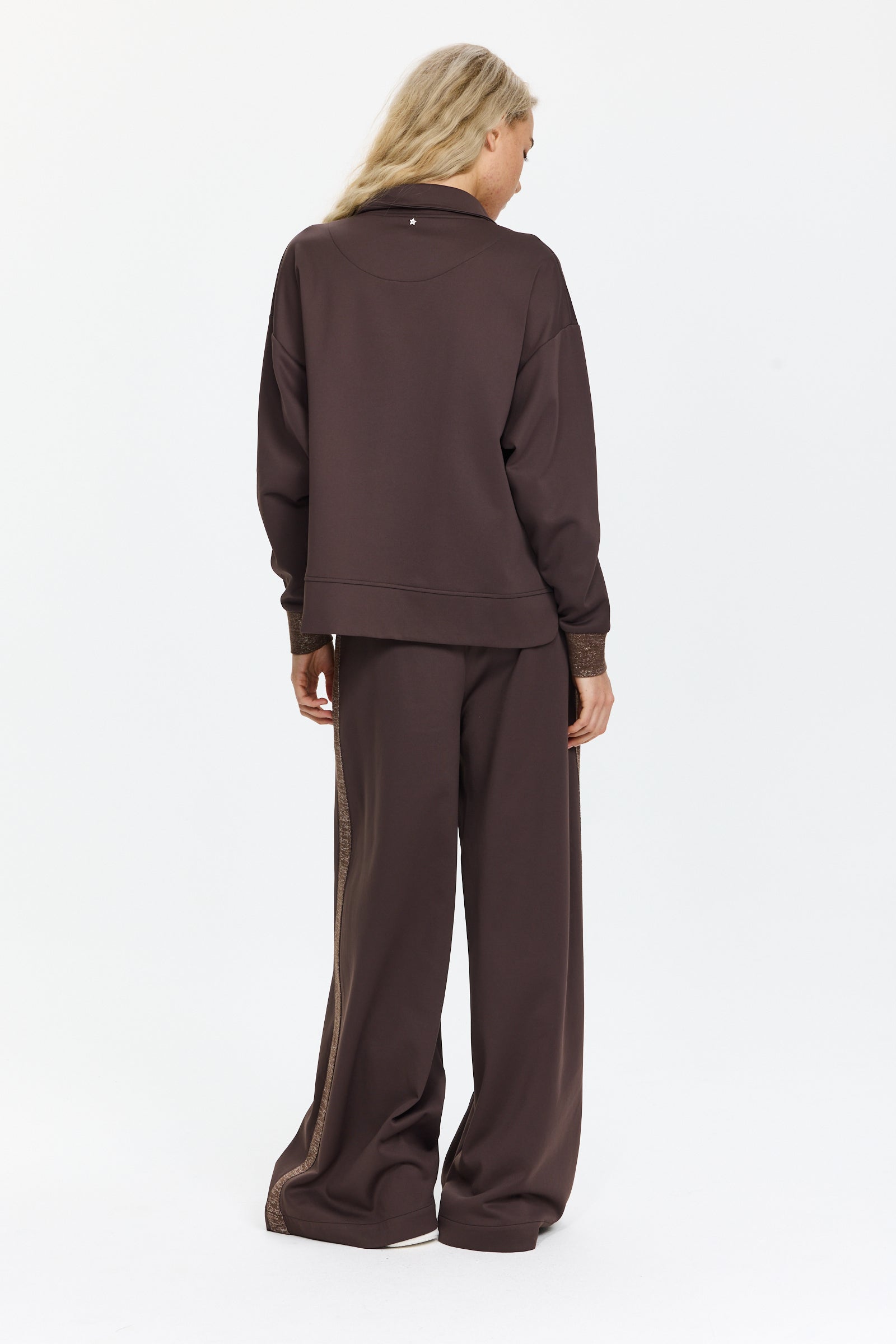 מכנסיים רחבים בצבע חום כהה עם כיסים צדדיים, מעוטרים בפסים מנצנצים לאורך הצדדיםהדוגמנית בגובה 1.75 ולובשת מידה 42 של Lorena Antoniazzi