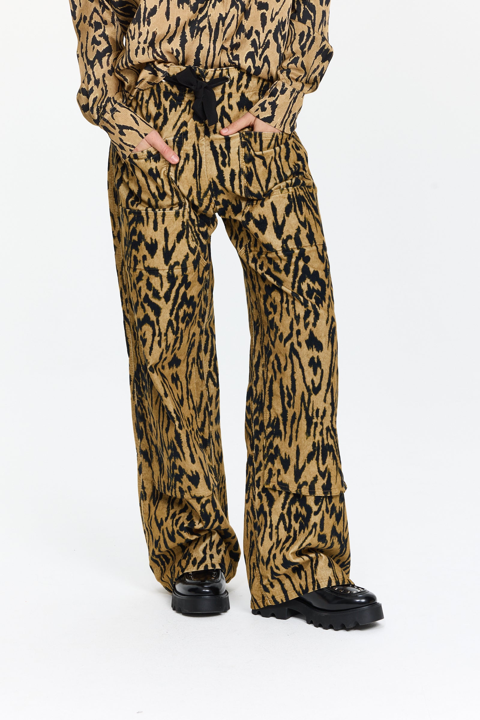 מכנסי קרגו מקטיפה עם הדפס שחור וטקסטורה עדינה.בעלי גזרה רחבה, כיסים צדיים, מותן עם גומי ושרוך קשירההרכב: 97% כותנה, 3% אלסטןהדוגמנית בגובה 1.75 ולובשת מידה 0 של Forte Forte