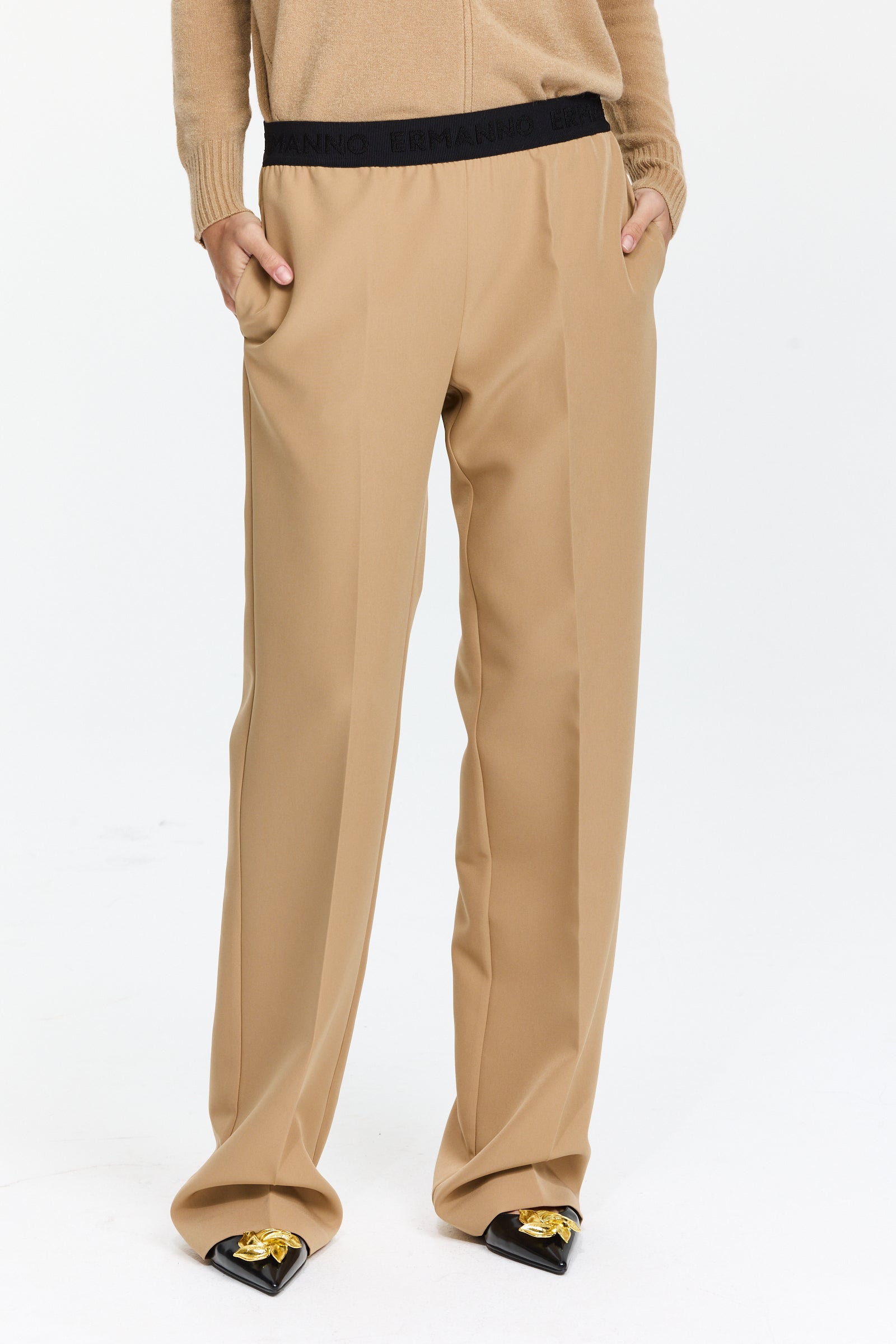 מכנסיים בצבע חום בז’ עם חגורת גומי, כיסים צדדיים, קפלים קדמיים וגזרה ישרה עד אמצע המותןהרכב בד: 89% פוליאסטר, 11% אלסטןהדוגמנית בגובה 1.75 ולובשת מידה 42 של Ermanno